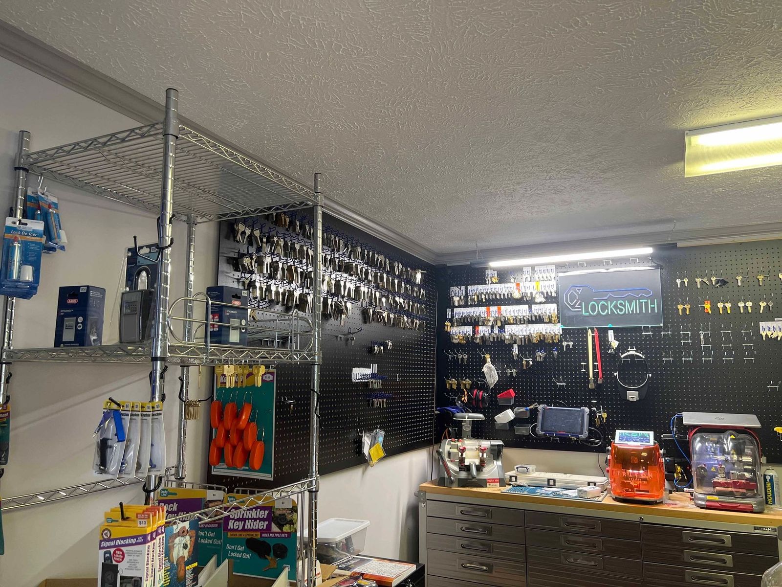 Locksmith shop interior; keys on pegboard, shelves of tools, work area.
